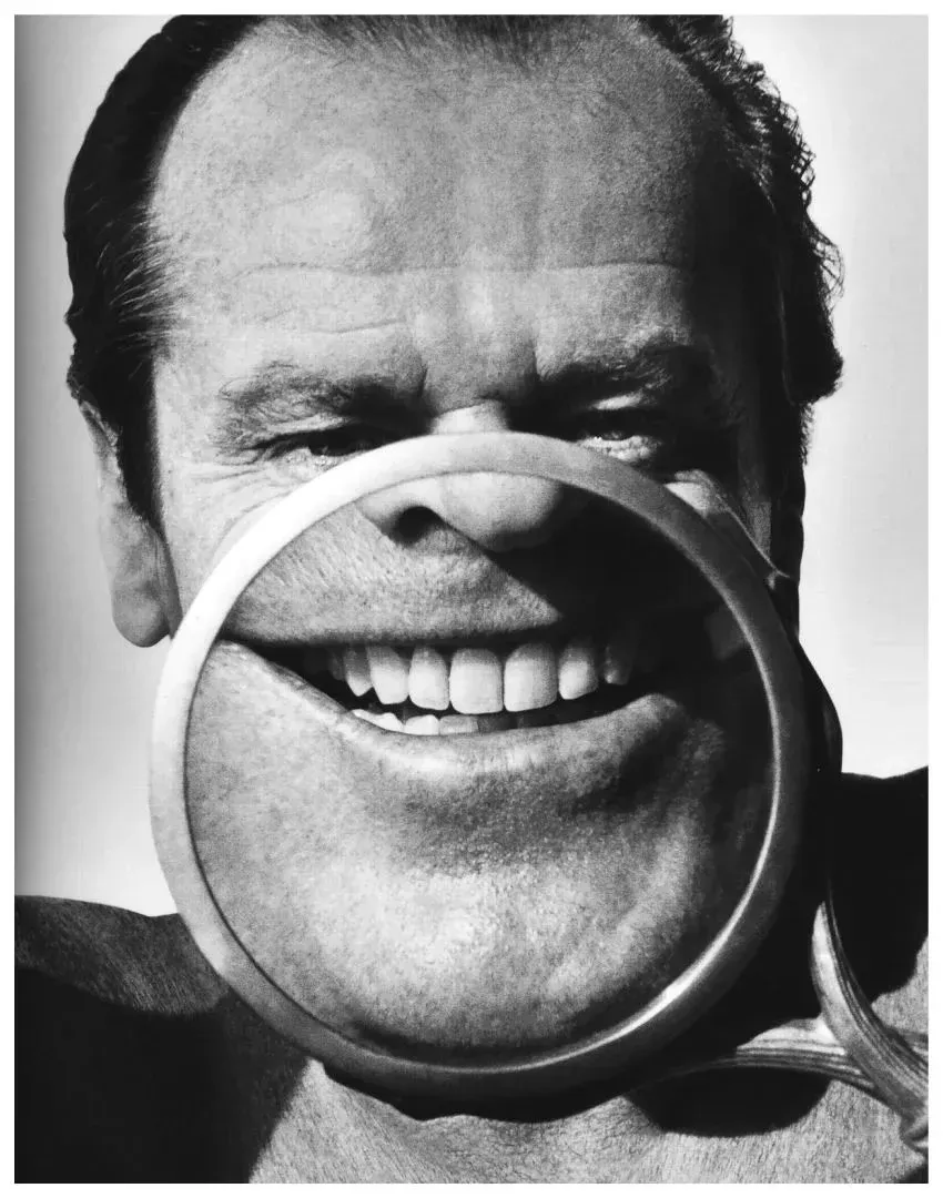 Retrato de un hombre riendo, con una lupa que deforma la mitad inferior de su cara
