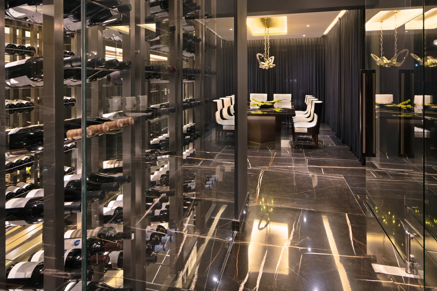Cava de vinos de piso a techo detrás de cristal, con la barra al fondo