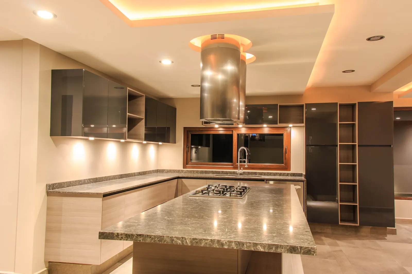 Cocina con isla, campana de acero y cubierta de granito