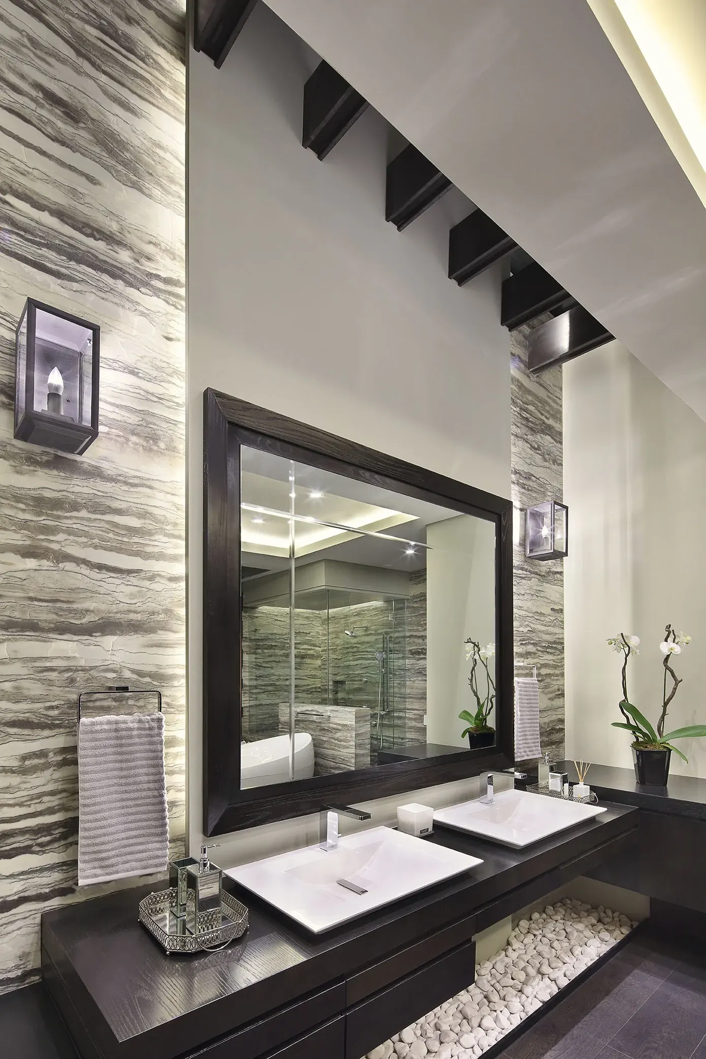 Baño con muro de piedra, espejo enmarcado y doble lavabo