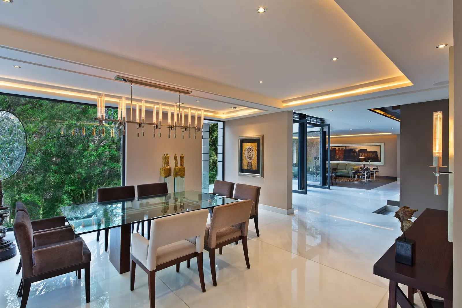 Comedor junto al ventanal, con la mesa de cristal y el jardín al fondo