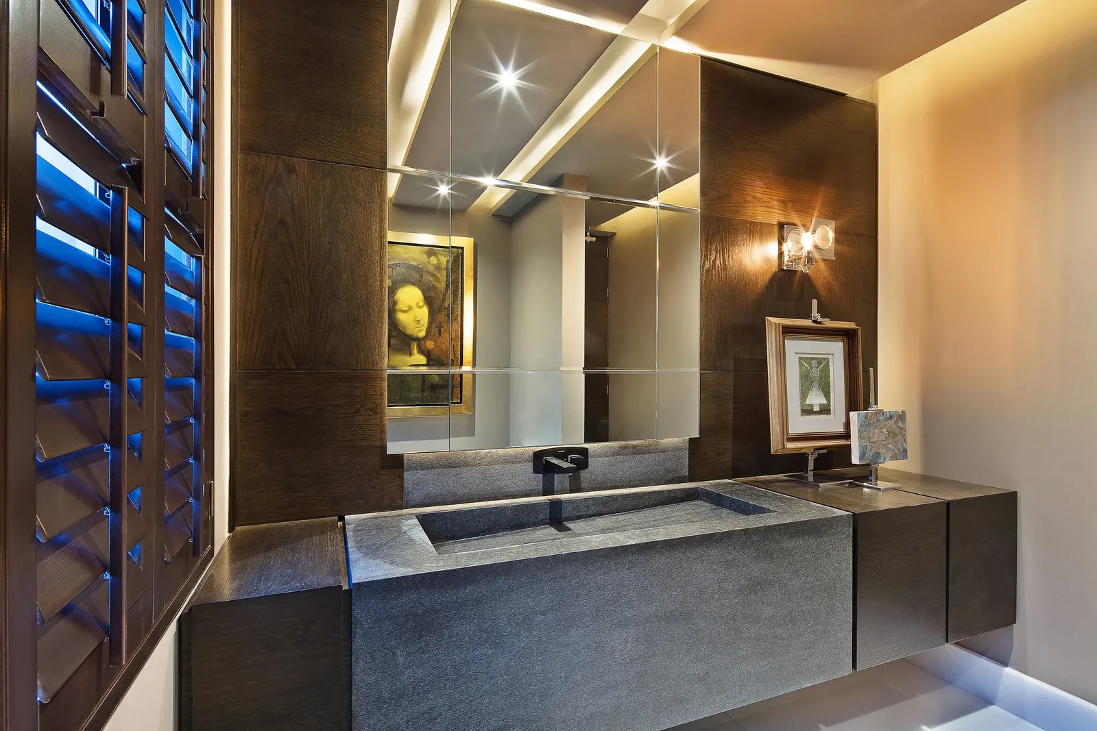 Baño con lavabo tallado en piedra y celosía de madera hacia el exterior