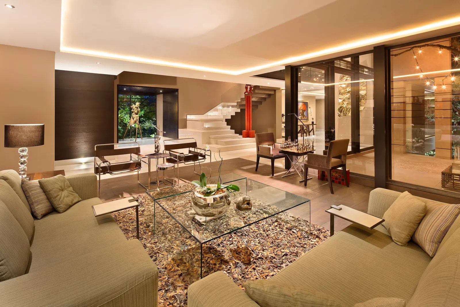 Sala con sofás claros y mesa de centro de cristal, abierta al vestíbulo