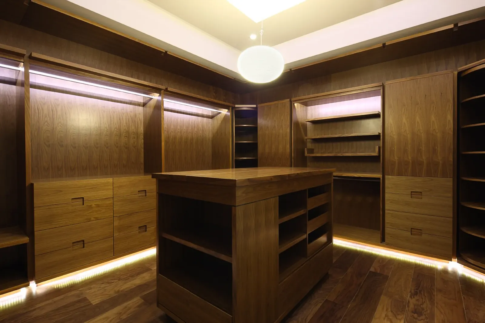 Vestidor con isla central y luz continua bajo los entrepaños