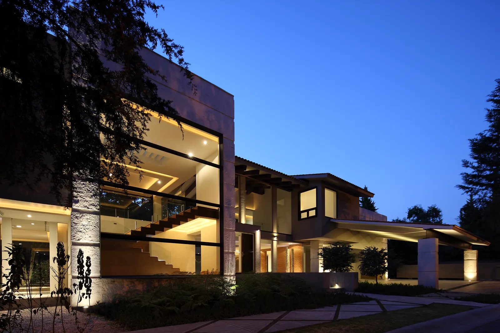 La casa al anochecer, con las estancias encendidas detrás del ventanal