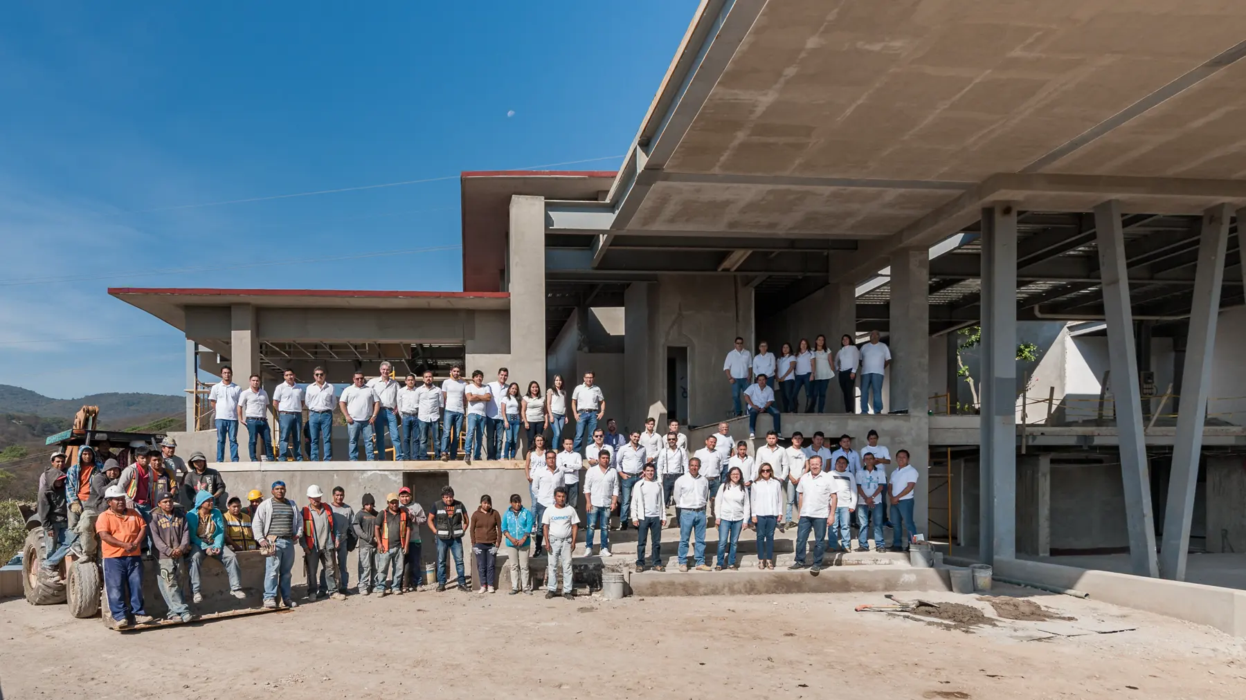 El equipo del despacho y la cuadrilla de obra reunidos frente a una casa en estructura